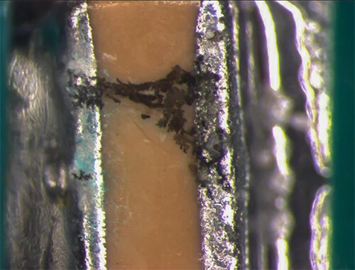 Dendritic grown between solder pads, caused by ionic contamination on printed circuit board